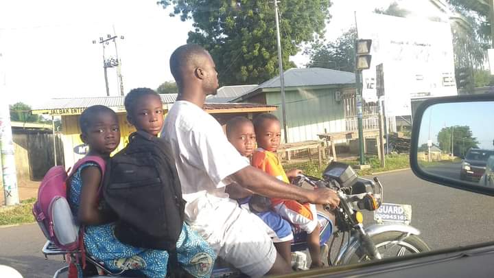 A father transports his four children on a motorbike in Wa, Upper West Region, Ghana.  (Shot over a car window photo credit; Dasmani Issifu Laary/GNA). 