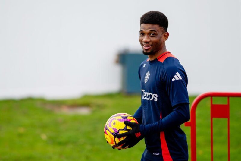 Amad Diallo smiles while holding a football